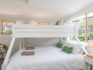 - une chambre avec des lits superposés dotés de draps blancs et d'oreillers verts dans l'établissement Tehidy Townhouse, à Kiama