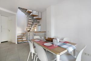 a dining room with a table and white chairs at Los Martínez Duplex in El Médano