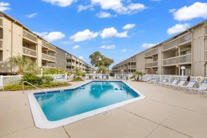 a swimming pool in the courtyard of a apartment building at Spacious Modern Condo - 1st Floor - One Block to the Beach in Myrtle Beach