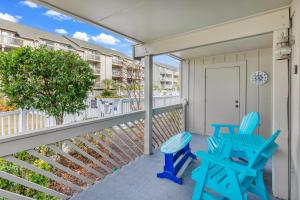 a balcony with two blue chairs and a door at Spacious Modern Condo - 1st Floor - One Block to the Beach in Myrtle Beach