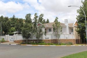 a white house with a fence at Florentia Guest House in Bloemfontein
