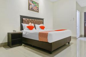 Kirei Hotel في Bonthain: غرفة نوم مع سرير كبير مع وسائد برتقالية