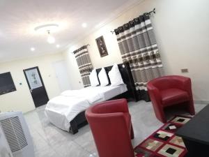 a bedroom with a bed and a red chair at Pentagon Hotel and Suites in Umueme