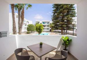 balcón con mesa, sillas y piscina en Holyhome premium 112, en Costa Teguise