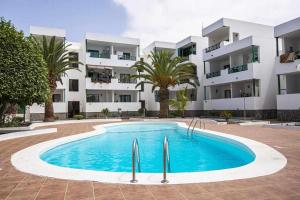 a swimming pool in front of a building at Holyhome premium 112 in Costa Teguise
