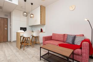 Una sala de estar con un sofá rojo y una mesa. en Business Center Apartments Warsaw Wola by Noclegi Renters, en Varsovia