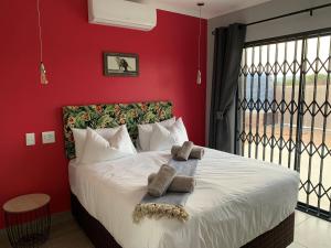 Elephant House, 2 bedroom House, Next to Pilanesberg and Sun City في Mogwase: غرفة نوم حمراء عليها سرير وفوط