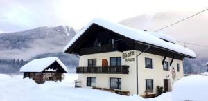 a building covered in snow with mountains in the background at Guesthouse Schoba Typ B in Oberdöbernitzen