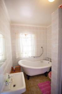 a white bathroom with a tub and a sink at Sneezewood in Dullstroom