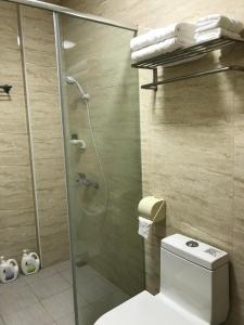 La salle de bains est pourvue d'une douche, de toilettes et d'une porte en verre. dans l'établissement Taitung Tourist Inn, à Taïtung