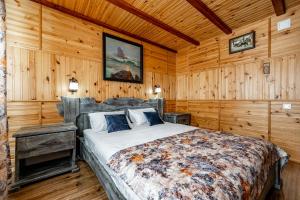 1 dormitorio con 1 cama en una habitación con paredes de madera en Emerald House en Mykulychyn