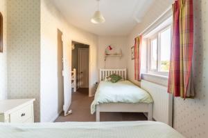 Habitación pequeña con 2 camas y ventana en Parnham Cottage, en Bridport