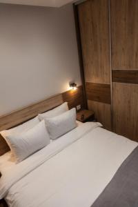 una camera da letto con un grande letto con lenzuola e cuscini bianchi di Per silvas apartman i spa a Zlatibor