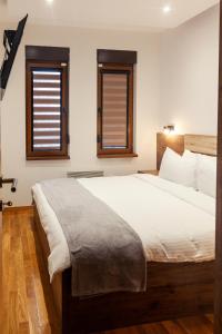 a bedroom with a large bed and two windows at Per silvas apartman i spa in Zlatibor