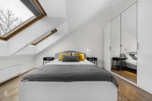 a white bedroom with a large bed with yellow pillows at Kaunas Old Town apartment with underground parking in Kaunas