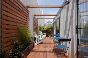 un patio con sillas y una mesa en una terraza de madera. en Oaktree House en Nelson