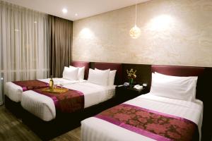 ein Hotelzimmer mit 2 Betten mit weißer und violetter Bettwäsche in der Unterkunft Goldberry Suites and Hotel Cebu in Cebu City