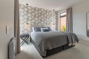 Un dormitorio con una cama grande con una pared de acento floral en Oaktree House, en Nelson