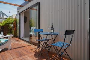 eine Terrasse mit blauen Stühlen und einem Tisch mit einer Flasche Wein in der Unterkunft Oaktree House in Nelson