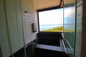 y baño con ventana y ducha con vistas. en 嵵裡仙人掌海景民宿Ocean view room, en Magong