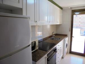 een keuken met witte kasten, een wastafel en een koelkast bij Apartamentos Alboran 4/6 LEK in Peñíscola