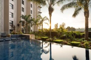 a swimming pool with palm trees and a building at Premier Hotel O.R. Tambo in Kempton Park
