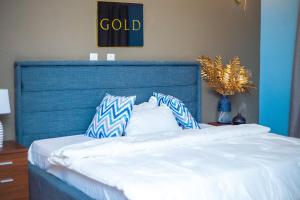 Bett mit blauem Kopfteil und Kissen darauf in der Unterkunft Piano & Gold Collections, Peduase in Peduasi