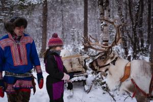 a man and a child standing next to a reindeer in the snow at Sorrisniva Arctic Wilderness Lodge in Alta