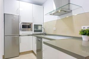 a kitchen with white cabinets and a stainless steel refrigerator at Genteel Home Encarnación in Seville