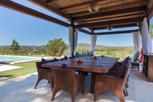 an outdoor dining room with a wooden table and chairs at Can Ribas Ibiza in Sant Llorenç de Balafia