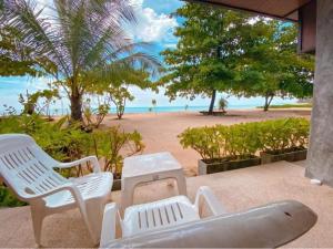 un grupo de sillas, una mesa y una playa en Dang Sea Beach Resort - SHA, en Nai Yang Beach