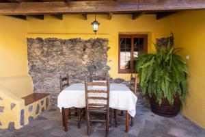 a dining room with a table and a stone wall at Home2Book Las Mimbreras in Agulo