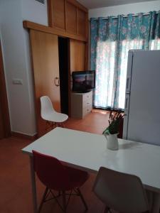 TV y cocina con mesa y sillas blancas. en Apartamento en puerta valle Ricote y Archena en Villanueva de Río Segura