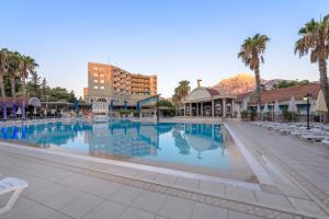 a large swimming pool at a resort with palm trees at Armas Kaplan Paradise in Tekirova