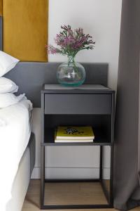 a nightstand with a vase of flowers and a book at Homewell Apartments Żelazko in Poznań