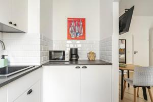 a kitchen with white cabinets and a table at Homewell Apartments Żelazko in Poznań +19 photos
