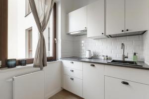 a white kitchen with white cabinets and a window at Homewell Apartments Żelazko in Poznań