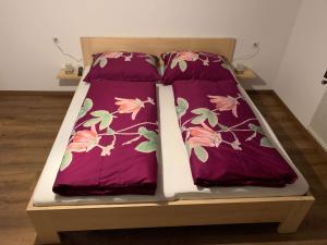 a bed with purple sheets and pink flowers on it at Ferienhaus "frainerei" in Klösterle