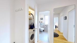 ein weißes Badezimmer mit Waschmaschine und Spiegel in der Unterkunft Ferienwohnung 3-Zimmer, 70 qm 3 Minuten zum Strand und Zentrum WHG Timme 3 in Timmendorfer Strand + 41 Fotos