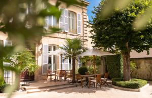 a patio with tables and umbrellas in front of a building at L'Hôtel in Beaune