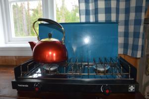 a tea kettle sitting on top of a stove at Hytte fra 1721 uten internett, strøm, vann - men med rødmalt utedo in Ljørdal