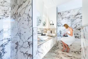 a woman in a white bathroom with a marble wall at Boutique Hotel Nice Côte d'azur in Nice