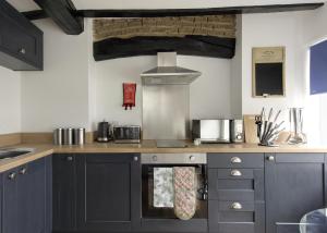 a kitchen with gray cabinets and a stove top oven at Donington Cottage Apt 4 in Castle Donington