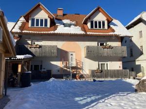 Una casa con nieve en el suelo delante de ella. en Aparthotel Pr' Jakapč', en Mojstrana