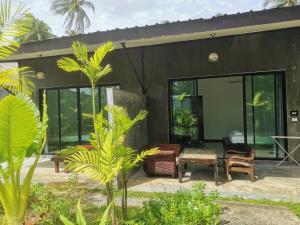 una casa negra con ventanas de cristal y mesa en Natai House en Natai Beach