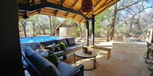 a patio with a couch and a swimming pool at Kubu Metsi Lodge in Matlhagame