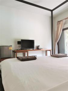 a bedroom with a large bed and a tv at Natai House in Natai Beach