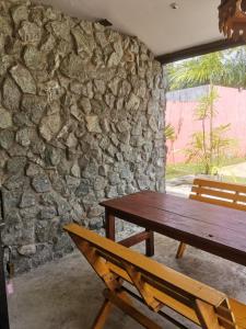 una mesa de madera y un banco frente a una pared de piedra en Natai House, en Natai Beach