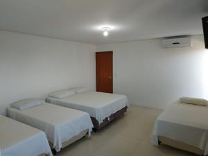 a hotel room with three beds and a television at Hotel Lírio in Carolina