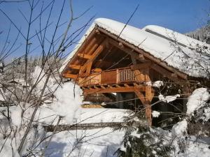 una cabaña de madera en la nieve en Chambres d'hôtes de charme Douglas en Samoëns